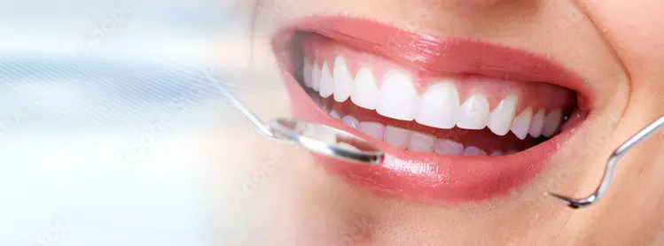 A woman with red lipstick and white teeth holding a tooth brush.