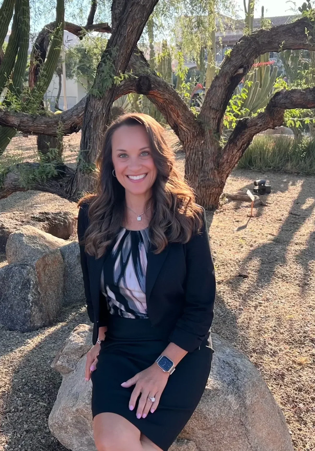 A woman sitting on top of a rock under a tree.